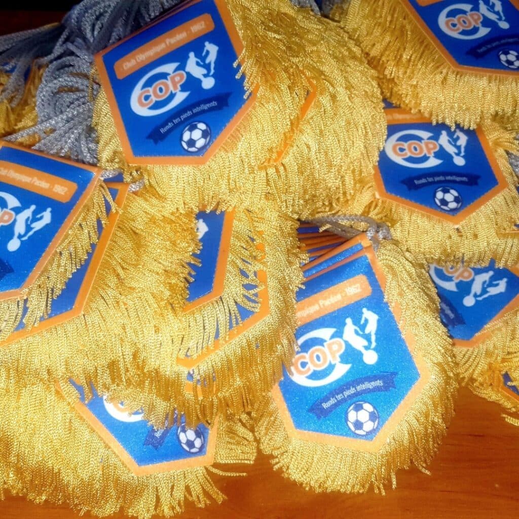 Fanions du Club Olympique Pacéen (COP) à franges dorées, logo football et slogan : Rends tes pieds intelligents.