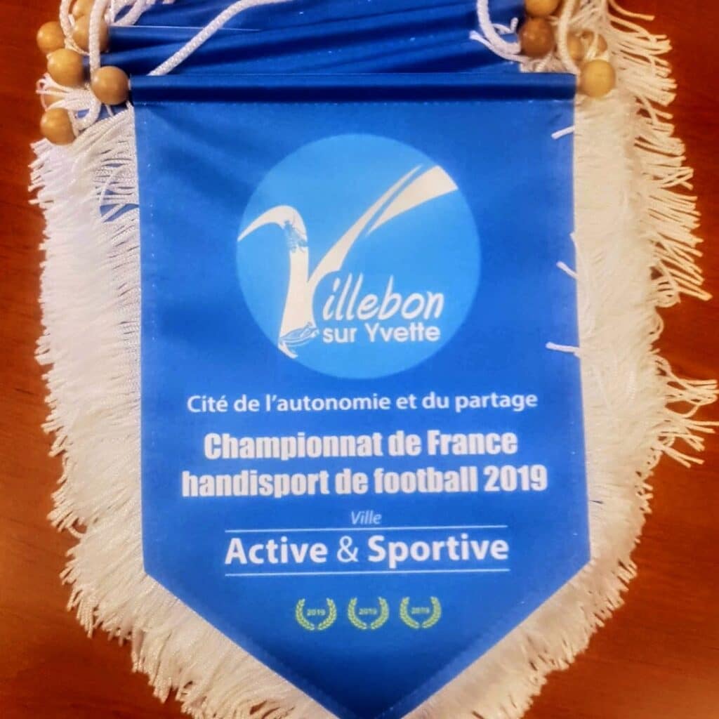 Fanion bleu du Championnat de France handisport de football 2019 à Villebon-sur-Yvette avec franges blanches.