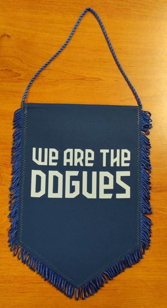 Fanion bleu LOSC avec franges et texte blanc 'WE ARE THE DOGUES' posé sur un support en bois.